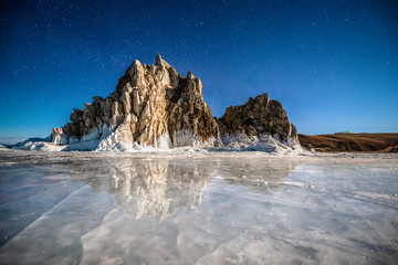 Landscape view of the mountain Shamanka with natural ice in frozen water at night star sky, Burkhan island Olkhon at Baikal lake, Russia
