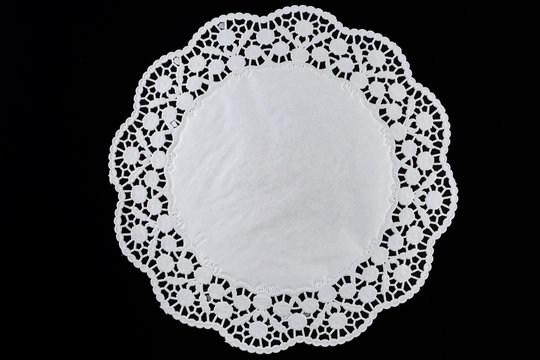 White paper round lace doily, on black background.