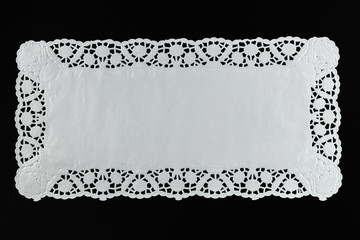 White paper lace doily, closeup on black background. - obrazy, fototapety, plakaty