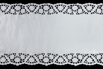 White paper lace doily, closeup on black background. - obrazy, fototapety, plakaty