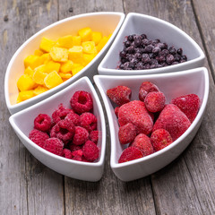 healthy berries and fruit in shaped bowls on wooden talbe