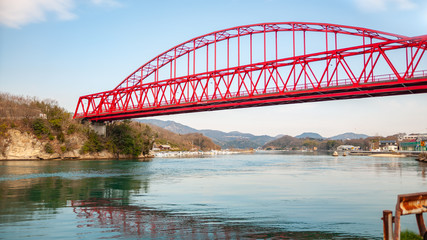 A red-colored bridge called 'Mukaishimao Bridge', which connects Mukoujima Island and Iwashi Island, along the Shimanami Kaido in the Shikoku Region in Japan.