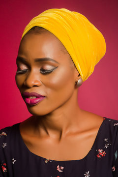 Portrait of a lady wearing yellow scarf on red background.