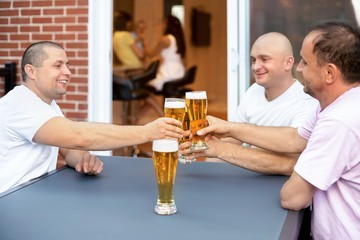 Three Happy male friends relax drinking beer night out home terrace. Friendship concept