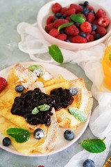 French crepes with blueberry compote topping, selective focus