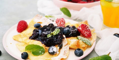 French crepes with blueberry compote topping, selective focus