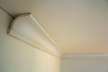 Close-up detail of decoration white molding connected with glue adhesive to wall and ceiling in interior room renovation and reconstruction. © bilanol