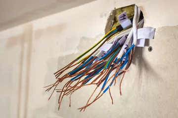Foto op Canvas Electrical exposed connected wires protruding from socket on white wall. Electrical wiring installation. Finishing works in renovated apartment. © bilanol