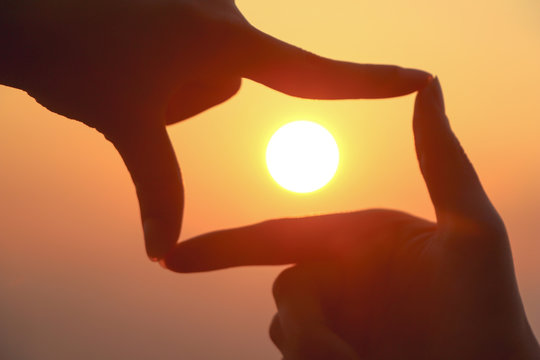 woman hands making frame gesture with sunrise on mountain background.