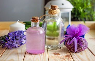  A glass transparent bottle with a organic cosmetic skin care product is placed in the center of the table, in the background there are white towels, incense sticks and white candles. Spa treatments