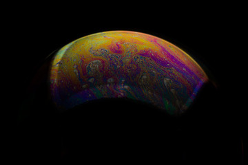 A bubble in rainbow colors on a black background.