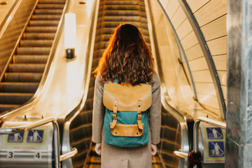 Young woman curly red head girl traveller with backpack and map in subway station in front of...