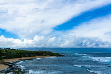 Maui beach with rolling waves and cloudy sky.