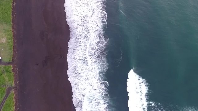 Aerial view of waves breaking on sandy beach.