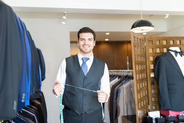 Fototapeta na wymiar Sales Clerk With Measuring Tape Looking At Camera