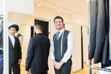 Fototapeta premium Designer Standing By Client Wearing Suit At Rental Store