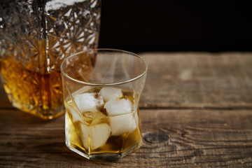 Whiskey with ice in glasses, rustic wood background, copy space 
