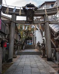 Ancient torii gate leading to Ushitora Shrine, with a Japanese lantern on the left which says "Ramen" on the left and the Ropeway Sanroku Station Tourist Information Center on the right.