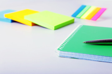 Modern white office desk table with laptop, smartphone and other supplies. Blank notebook page for input the text in the middle. Top view.