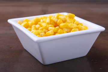 Sweet canned corn in white bowl. Ingredients for salad. Selective focus.
