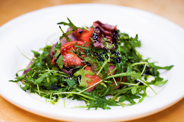 Salad with pieces of marbled beef and arugula on a white plate