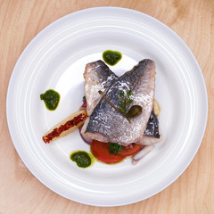 Grilled Dorado fish with onion and lemon slice on white plate