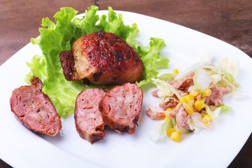 Marinated roaste chicken breasts cooked on BBQ and served with fresh salad on white plate, close up.
