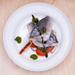 Grilled Dorado fish with onion and lemon slice on white plate