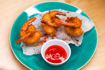 Deep fried king prawns with spicy sauce on a blue plate