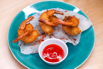 Deep fried king prawns with spicy sauce on a blue plate