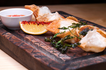 Fried dumplings with spicy sauce on a wooden tray