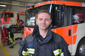 Portrait Feuerwehrmann vor einem Feuerwehrauto // portrait of a firefighter in the operations...