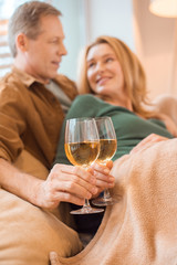 selective focus of happy couple clinking glasses of white wine