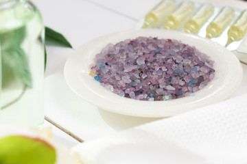 Colourful sea salt with cosmetic oils and white towel