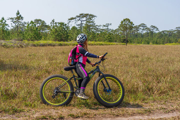 Asian female cyclist standing on mountain bike with nature background