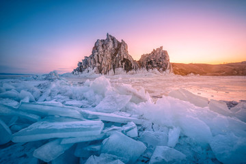 Landscape of Shamanka rock at sunrise with natural breaking ice in frozen water on Lake Baikal,...