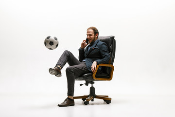 Businessman with football ball in office. Soccer freestyle. Concept of balance and agility in...