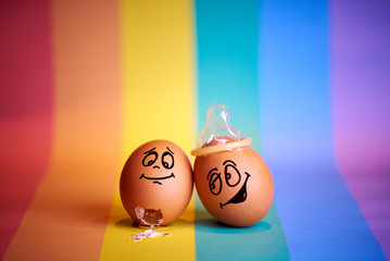 A couple of chicken eggs with a satisfied face on the background  on a  flag  LGBT.