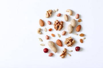 Assorted nuts on a white table. Hazelnuts, cashews, peanuts, walnuts, almonds.