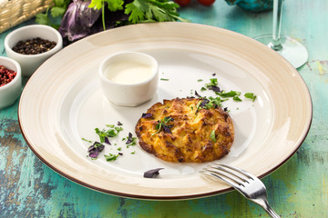 Zucchini pancakes with greens and sour cream on blue wooden table