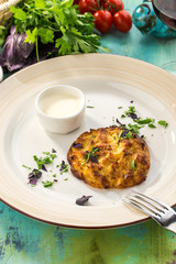 Zucchini pancakes with greens and sour cream on blue wooden table