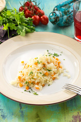 boiled rice with vegetables on white plate on blue wooden table