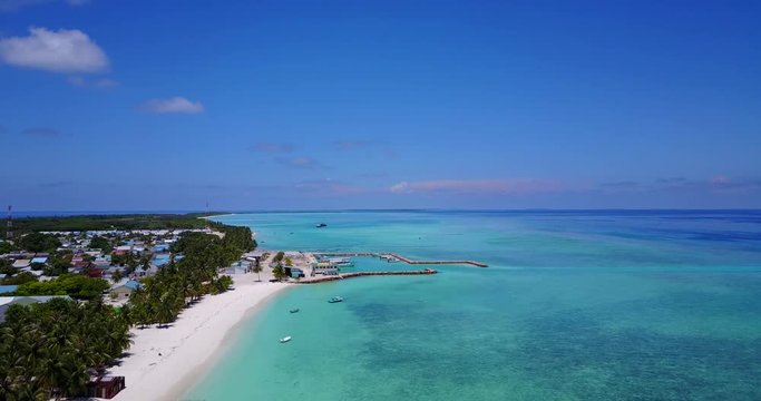 Aerial flying towards village harbor on isolated Maldives island