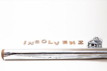 Insolvenzschriftzug mit Aluminiumfolie im Vordergrund