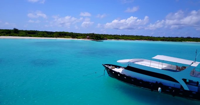 aerial view of a power boat anchored close to a Caribbean island with a white sandy beach and turquoise water