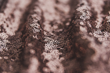 Brown shiny fabric with sequins, abstract background.
