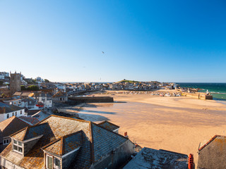 Wide view of St Ives town, beach and harbour as sunset approaches.