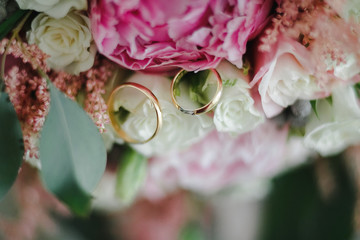 Two yellow gold wedding rings on the background of the flowers.