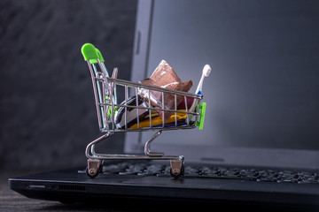 Daily purchases in the shopping cart on the laptop keyboard on a dark background. Shopping in online stores
