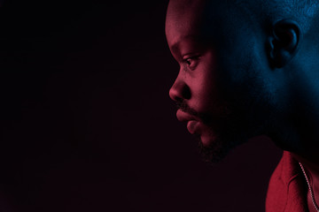 Close-up portrait of handsome man with beard in profile. Studio shot, black background, pink and blue light, neon - 253572890